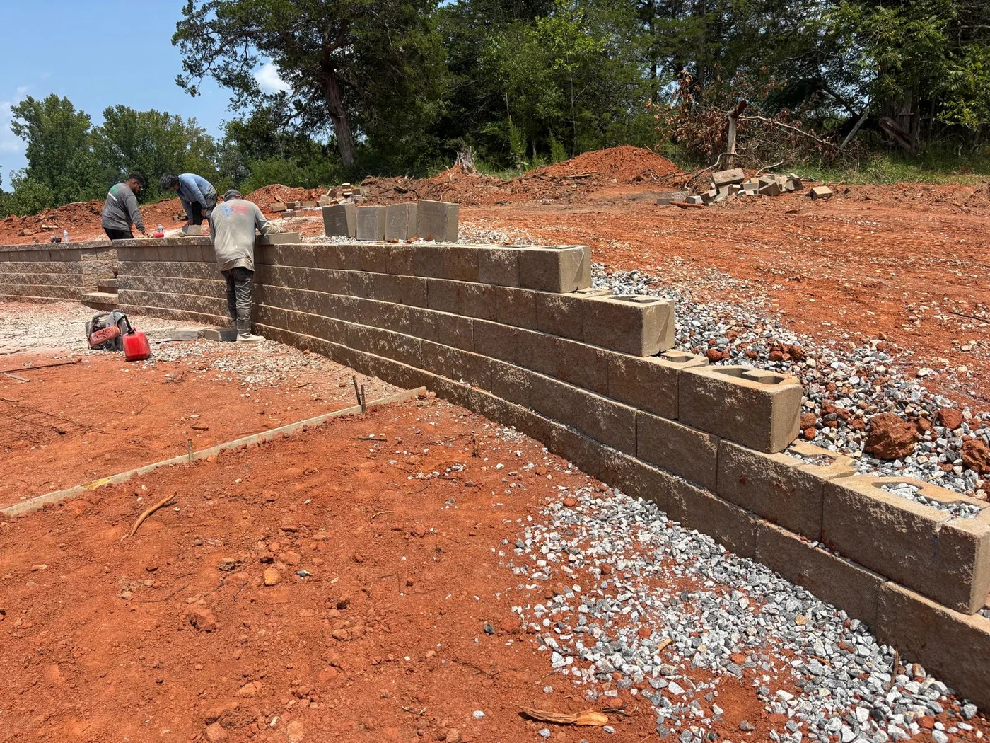 Retaining wall installation in progress with gravel base and crew